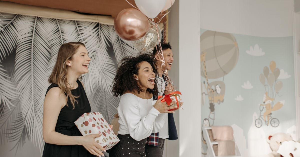 people singing happy birthday song holding gifts and balloons